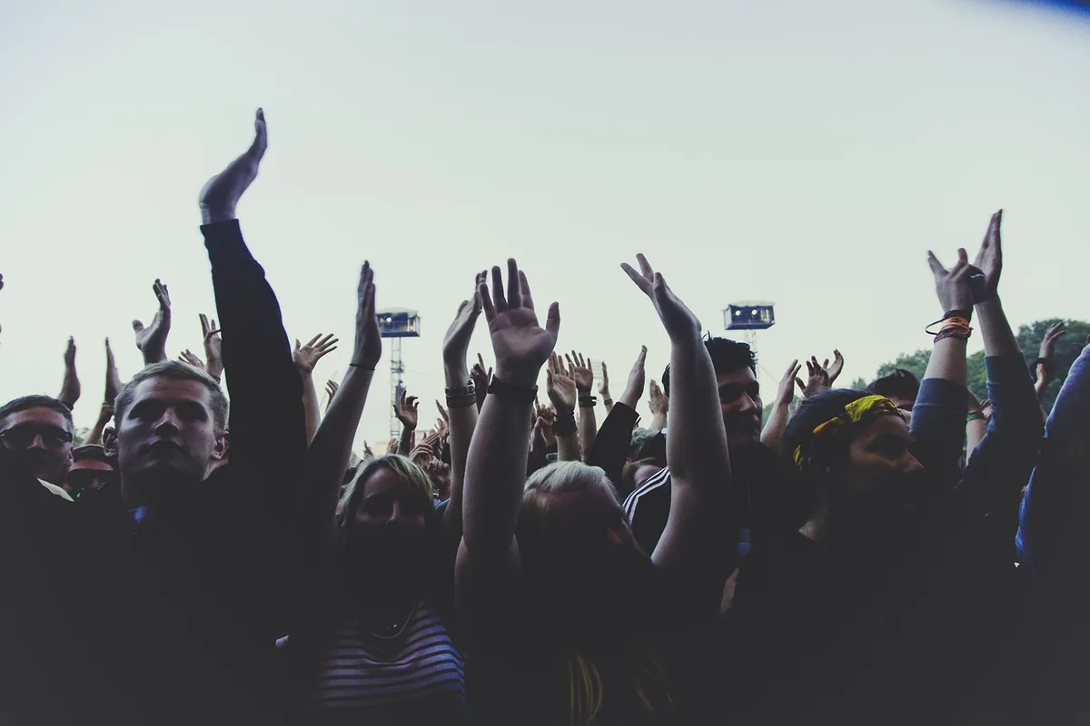 Silhouettes of audience members raising hands at a town-hall style event