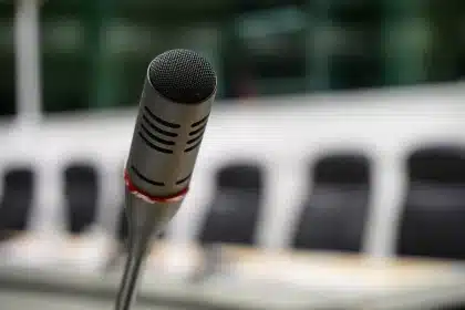 Empty press room with microphones and notebook on a table in front of a podium