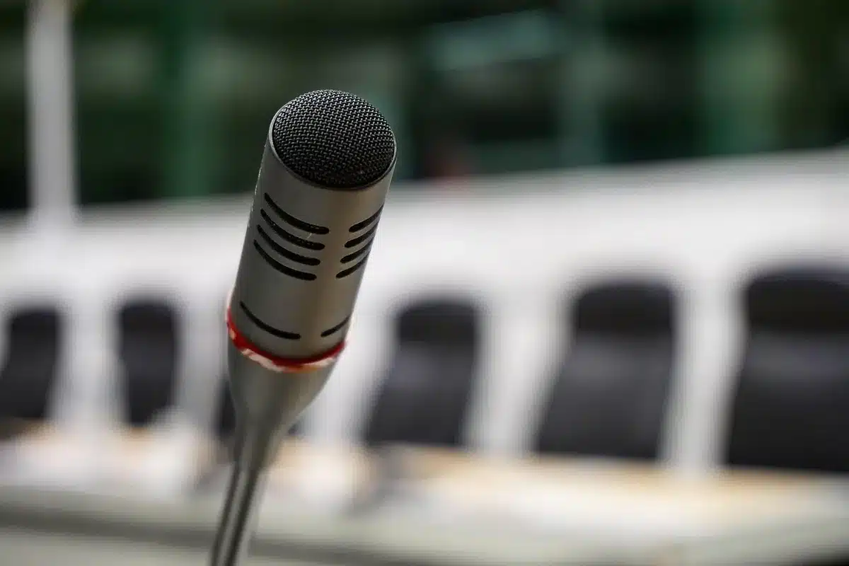 Empty press room with microphones and notebook on a table in front of a podium