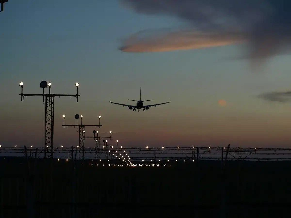 Silhouette of a large arch near a river with an airport runway in the distance