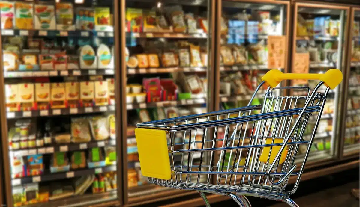 Person pushing grocery cart in a supermarket aisle, illustrating grocery tax relief
