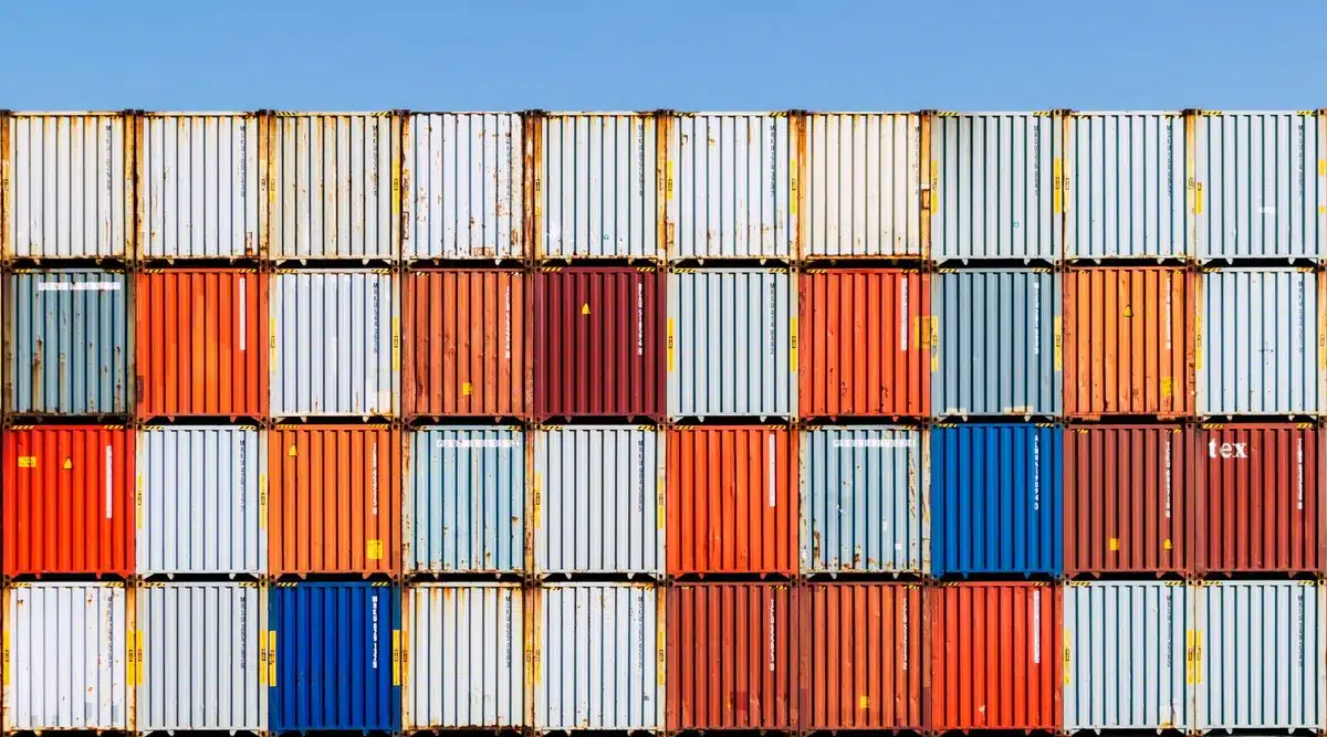 Boxes and shipping containers at a port and factory components showing import supply links
