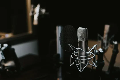 Anonymized podcast setup with microphone, books and mug on a small table in a studio