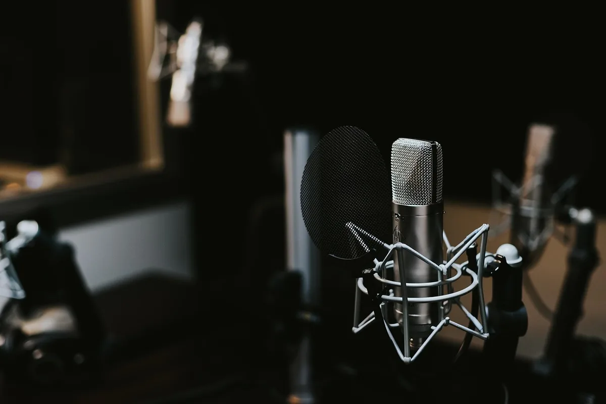 Anonymized podcast setup with microphone, books and mug on a small table in a studio