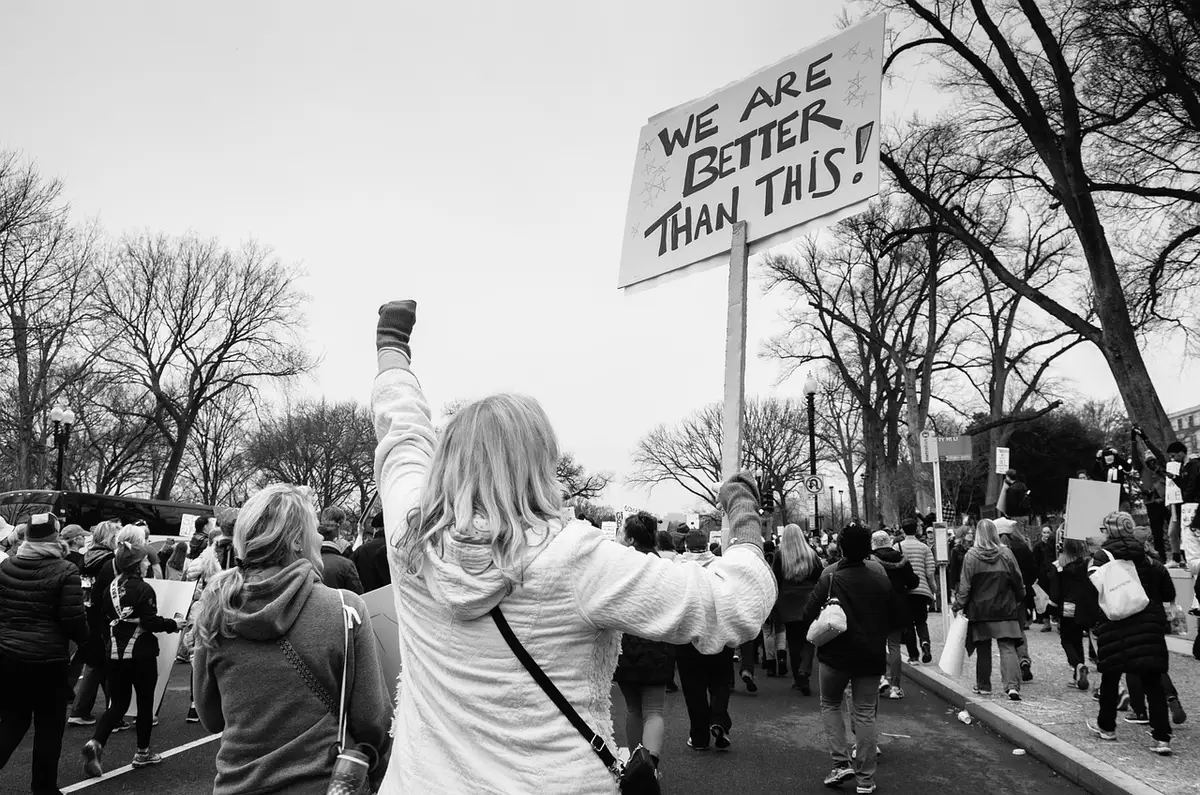 Anonymous crowd of protesters with homemade signs in a city plaza