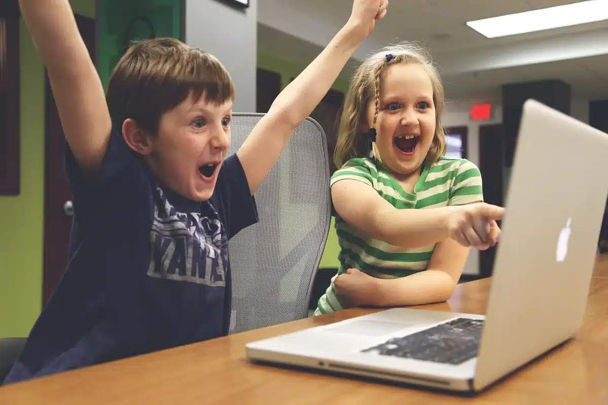 Parent checking a child's online account on a laptop with a piggy bank nearby
