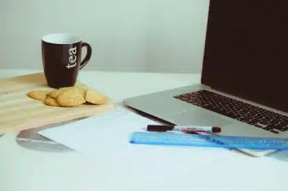 Desk with laptop showing a news roundup, mug and notepad
