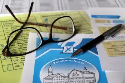 Folded ballots on a polling table with hands organizing them in a polling station