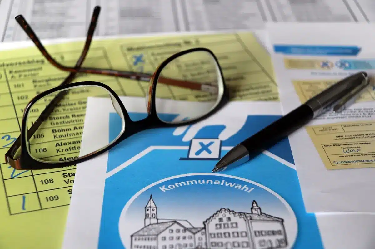 Folded ballots on a polling table with hands organizing them in a polling station