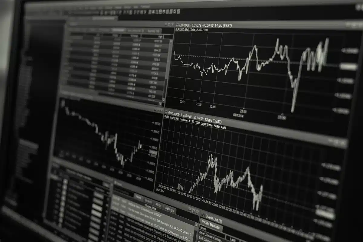 Person reviewing compliance documents beside a laptop with crypto charts